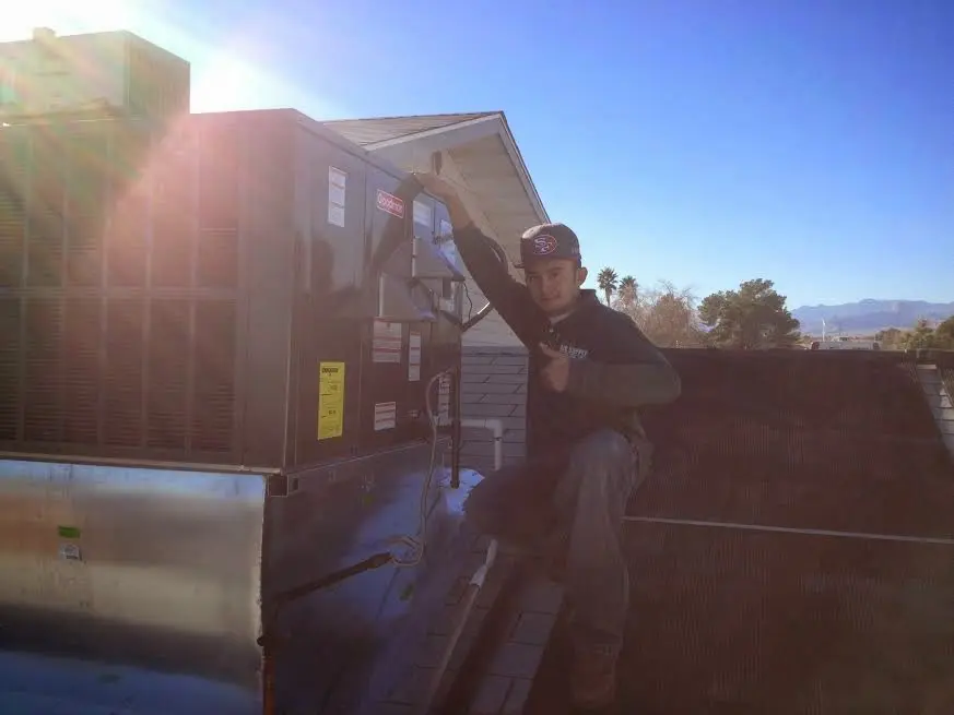 HVAC technician performing Air Duct Repair on a rooftop unit in Arlington