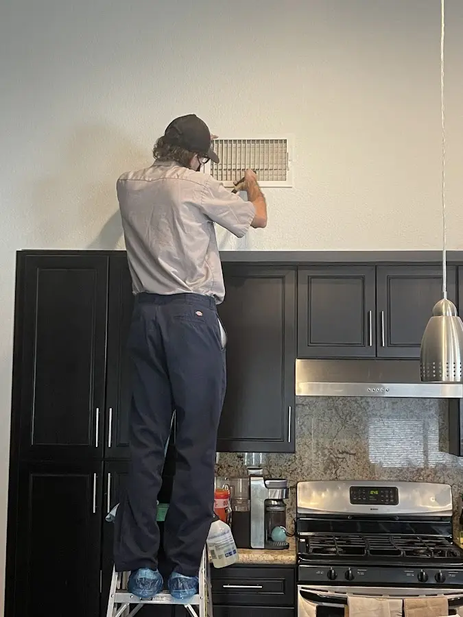 Technician inspecting an air vent during HVAC service in Arlington